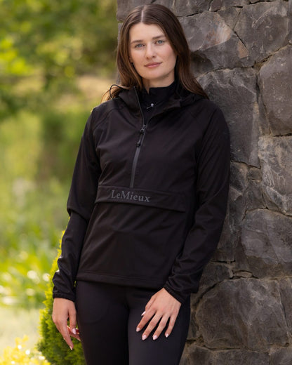 Black coloured LeMieux Womens Perri Half Zip Waterproof Jacket on tree background 