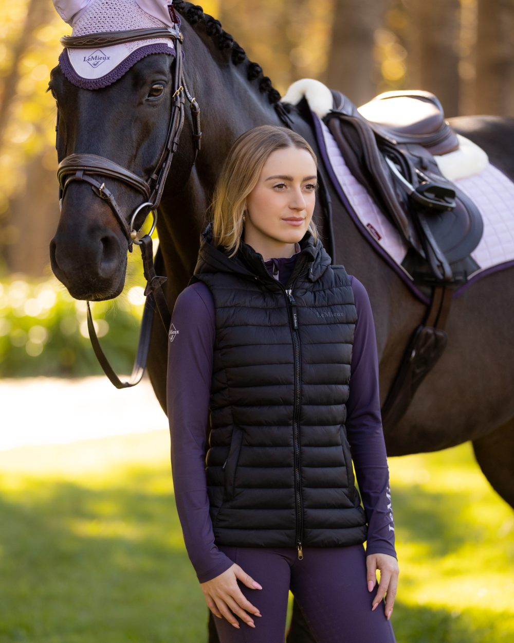 Black coloured LeMieux Womens Rose Hooded Puffer Gilet on blurry background 