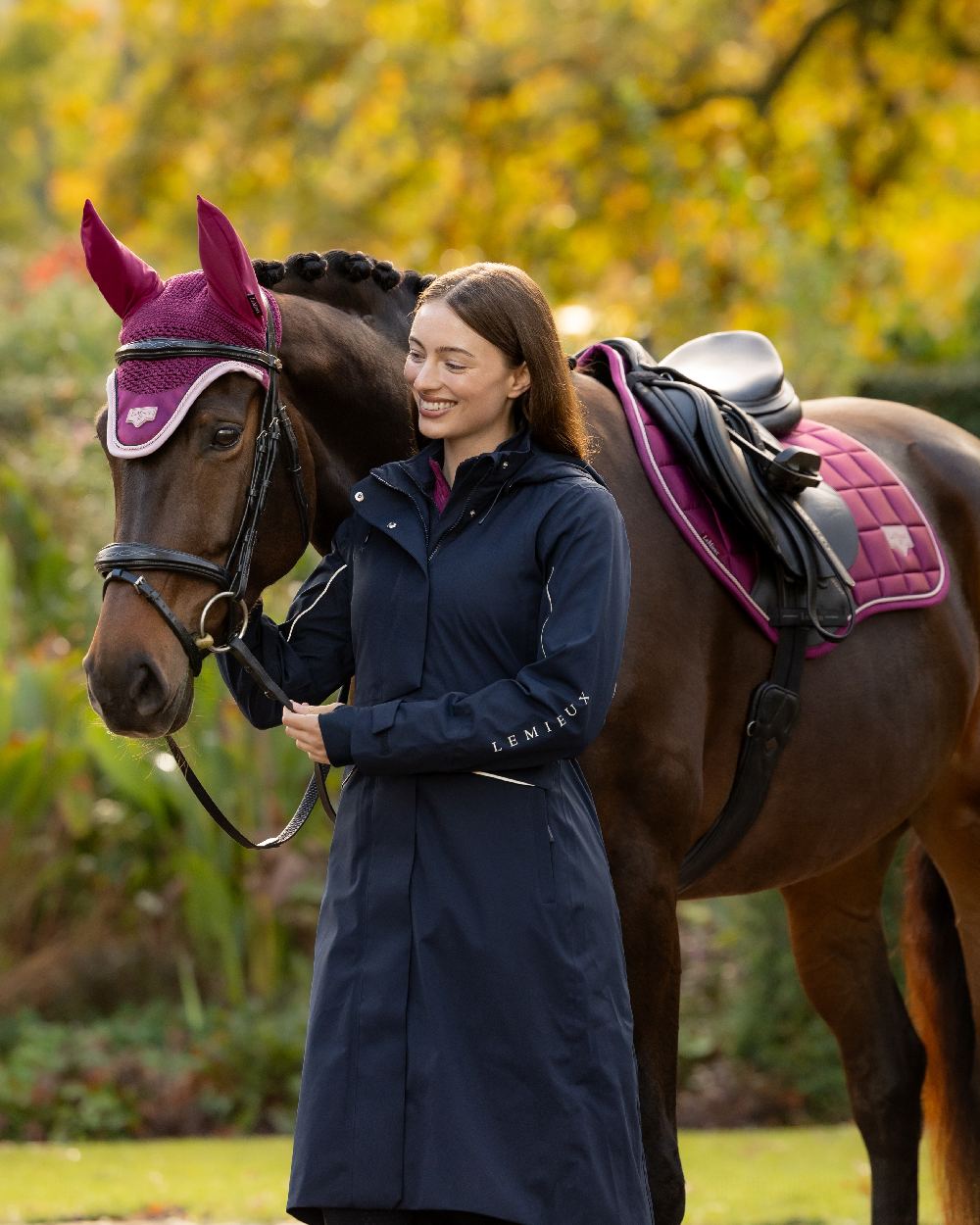 Navy Coloured LeMieux Womens Stormwear Performance Riding Coat on Yellow Autumn Leaves with Horse Background 