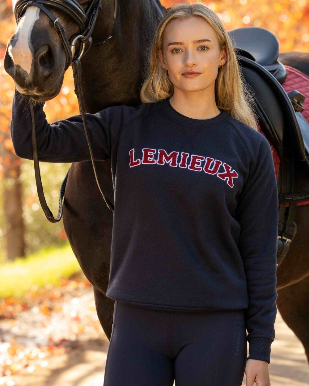 Navy coloured LeMieux Womens Vida Varsity Crew Neck Sweatshirt on outdoor background 