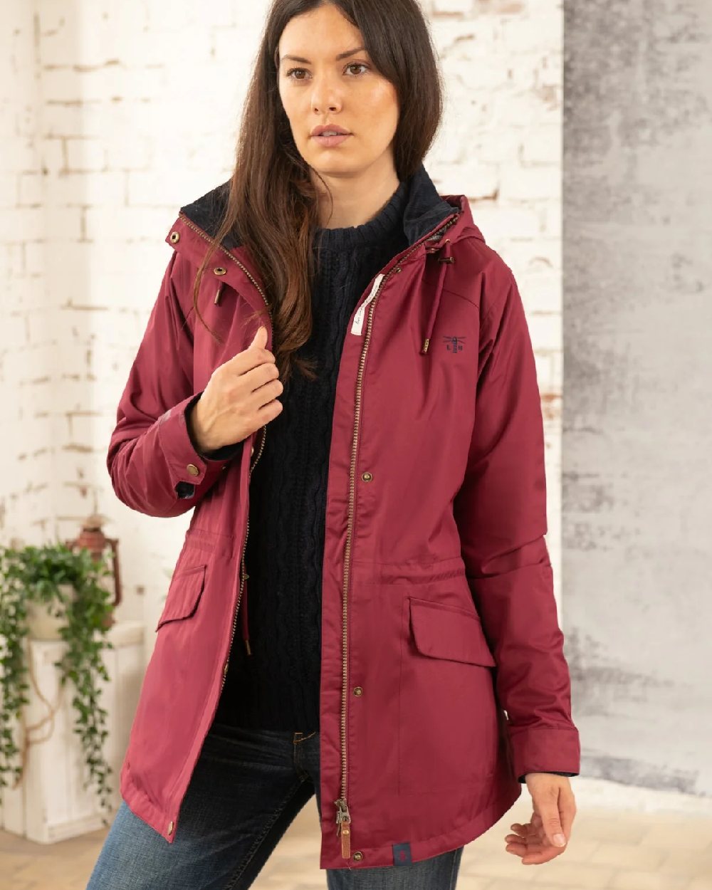 Berry coloured Lighthouse Kendal Waterproof Coat on wall background 