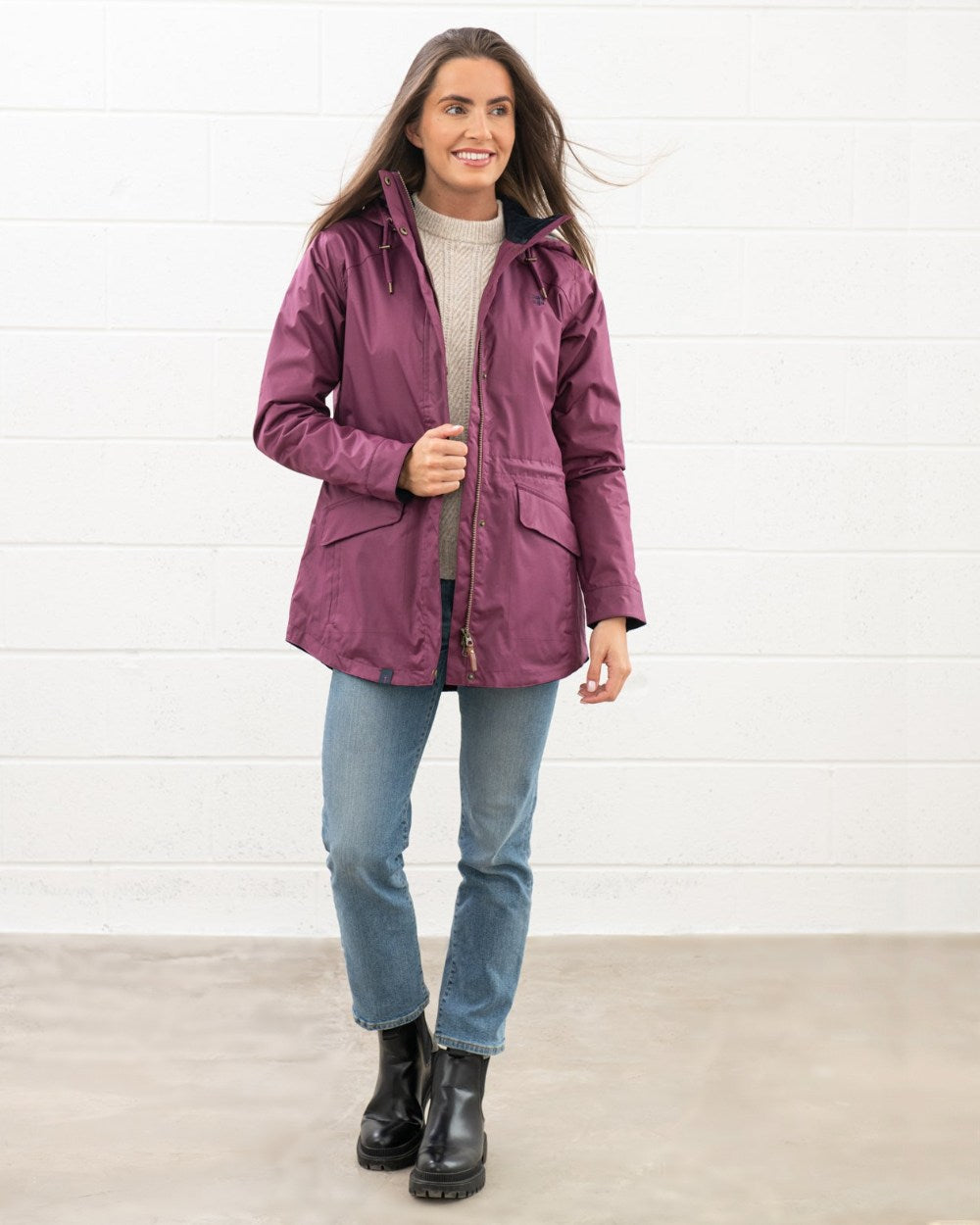 Plum coloured Lighthouse Kendal Waterproof Coat on wall background 