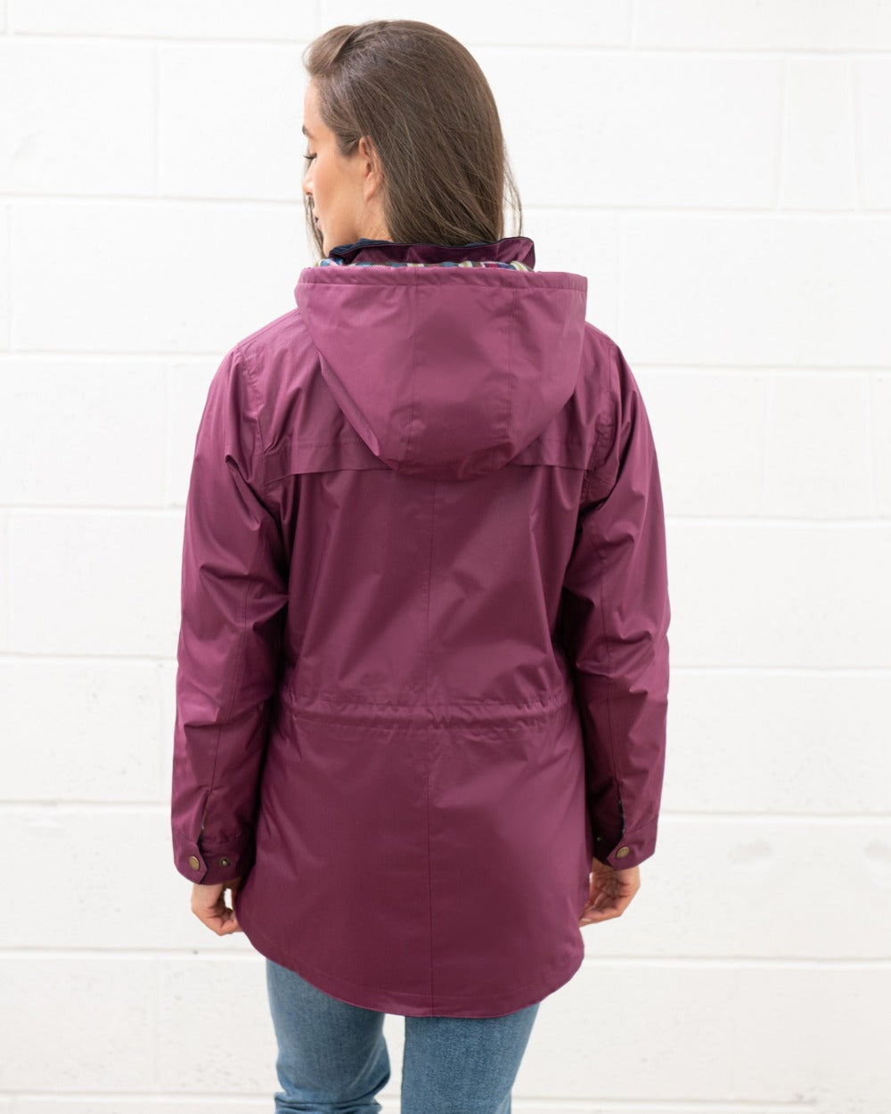 Plum coloured Lighthouse Kendal Waterproof Coat on wall background 