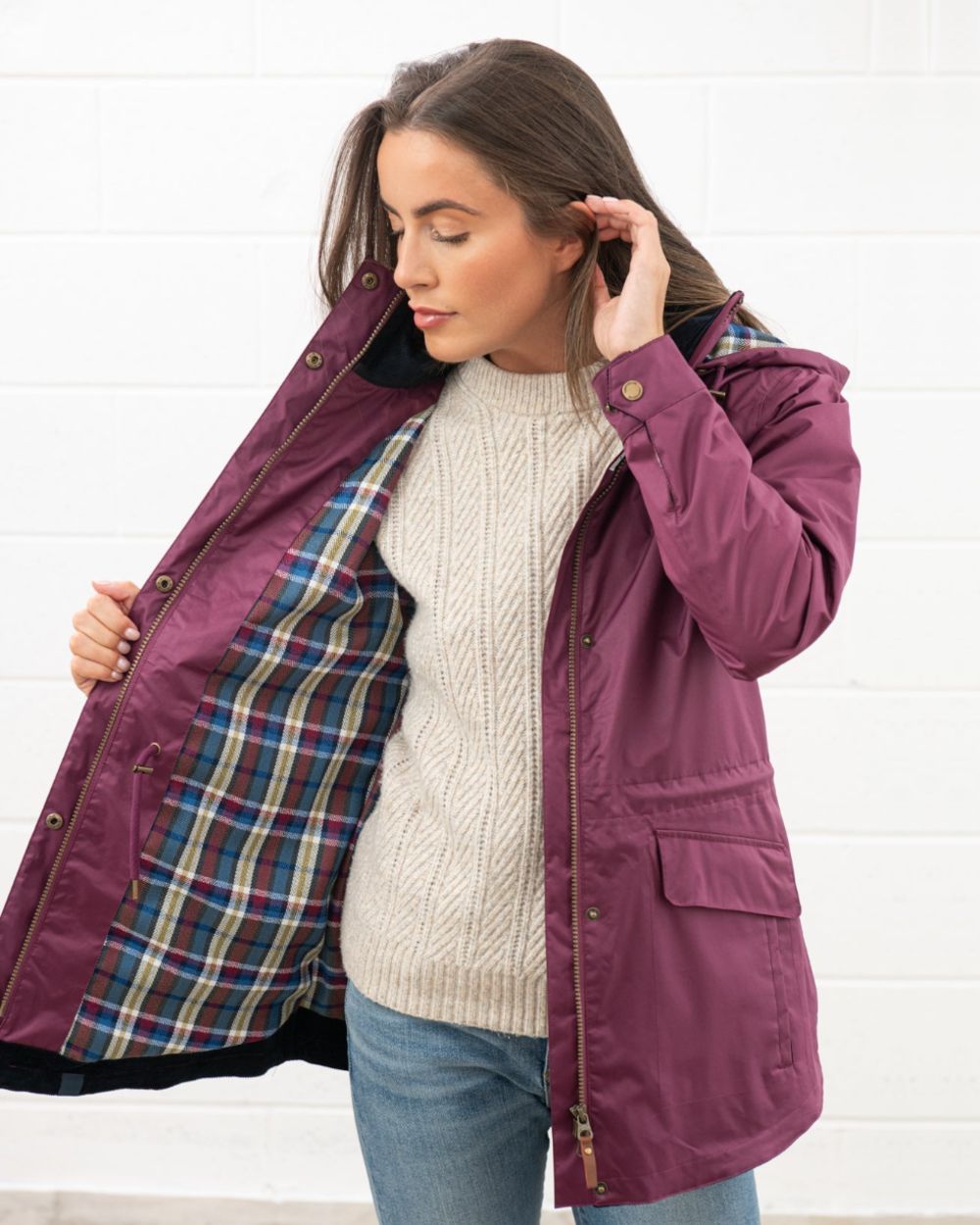 Plum coloured Lighthouse Kendal Waterproof Coat on wall background 