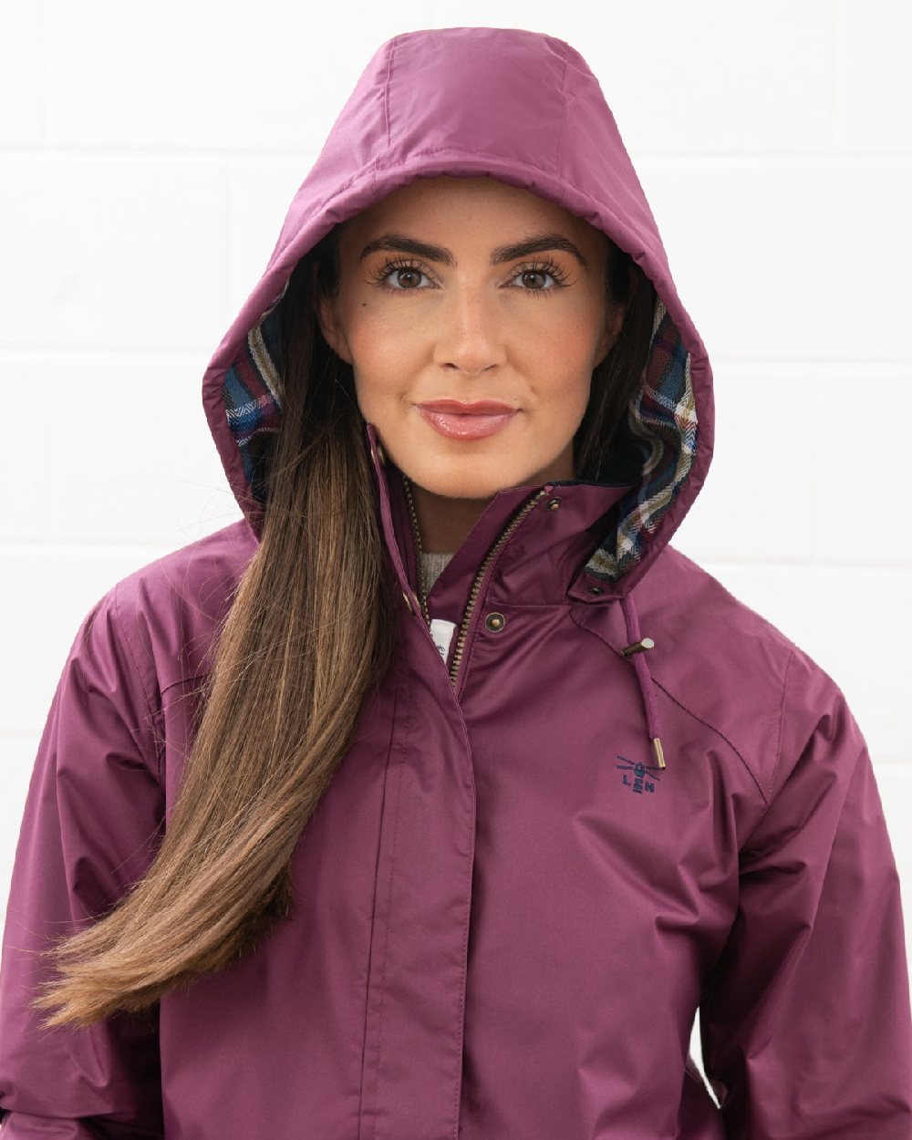 Plum coloured Lighthouse Kendal Waterproof Coat on wall background 