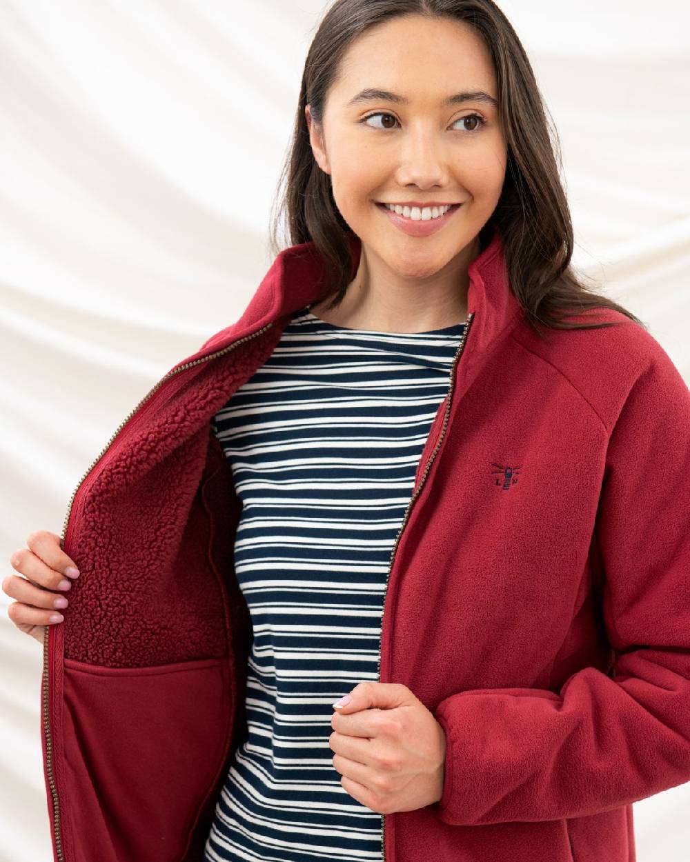 Maroon coloured Lighthouse Ladies Avon Waterproof Fleece on curtain background 