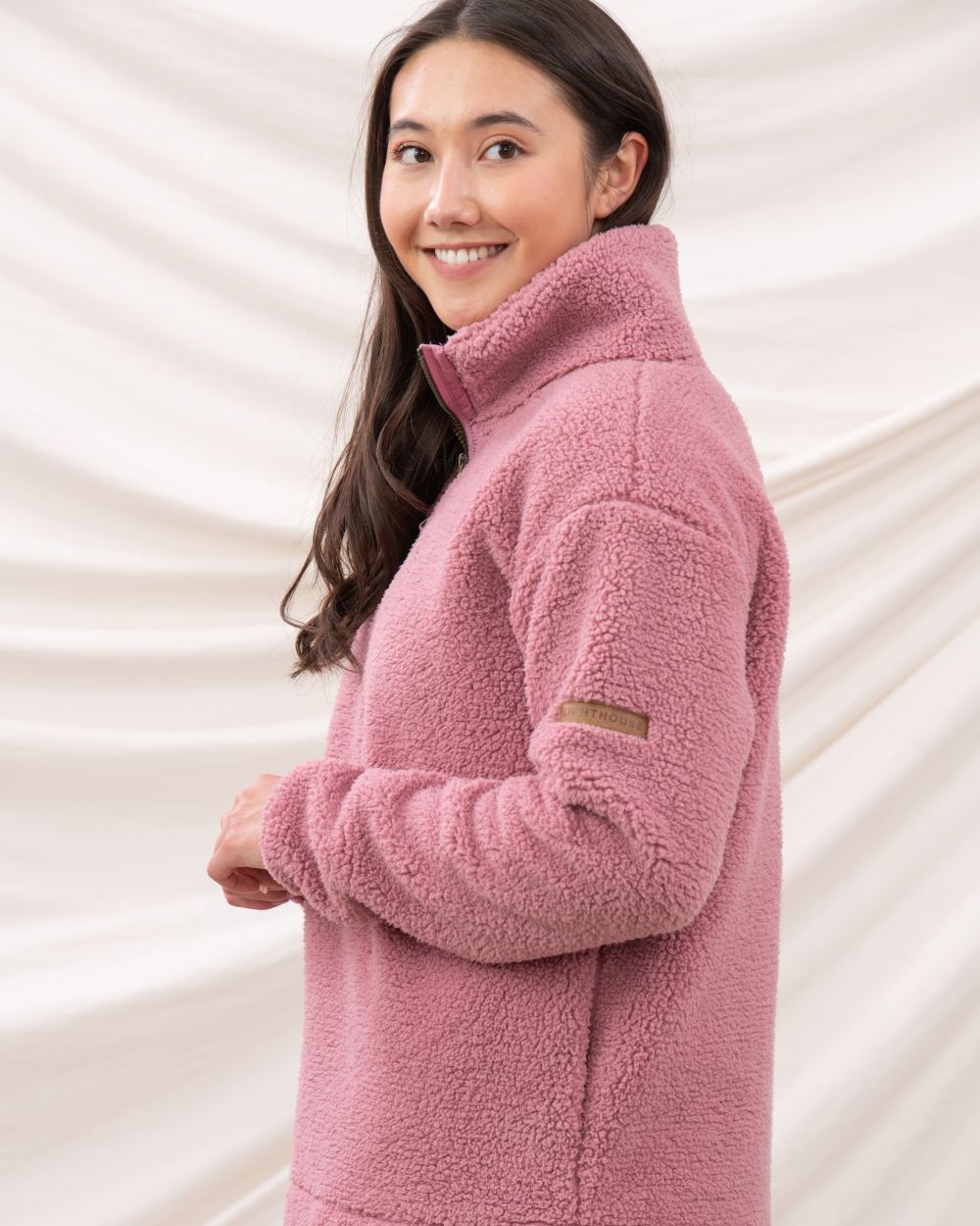 Wild Rose coloured Lighthouse Ladies Coast Half Zip Fleece Sweater on curtain background 