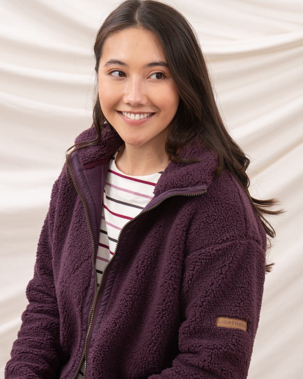 Cranberry coloured Lighthouse Ladies Cobh Full Zip Fleece Jacket on curtain background 