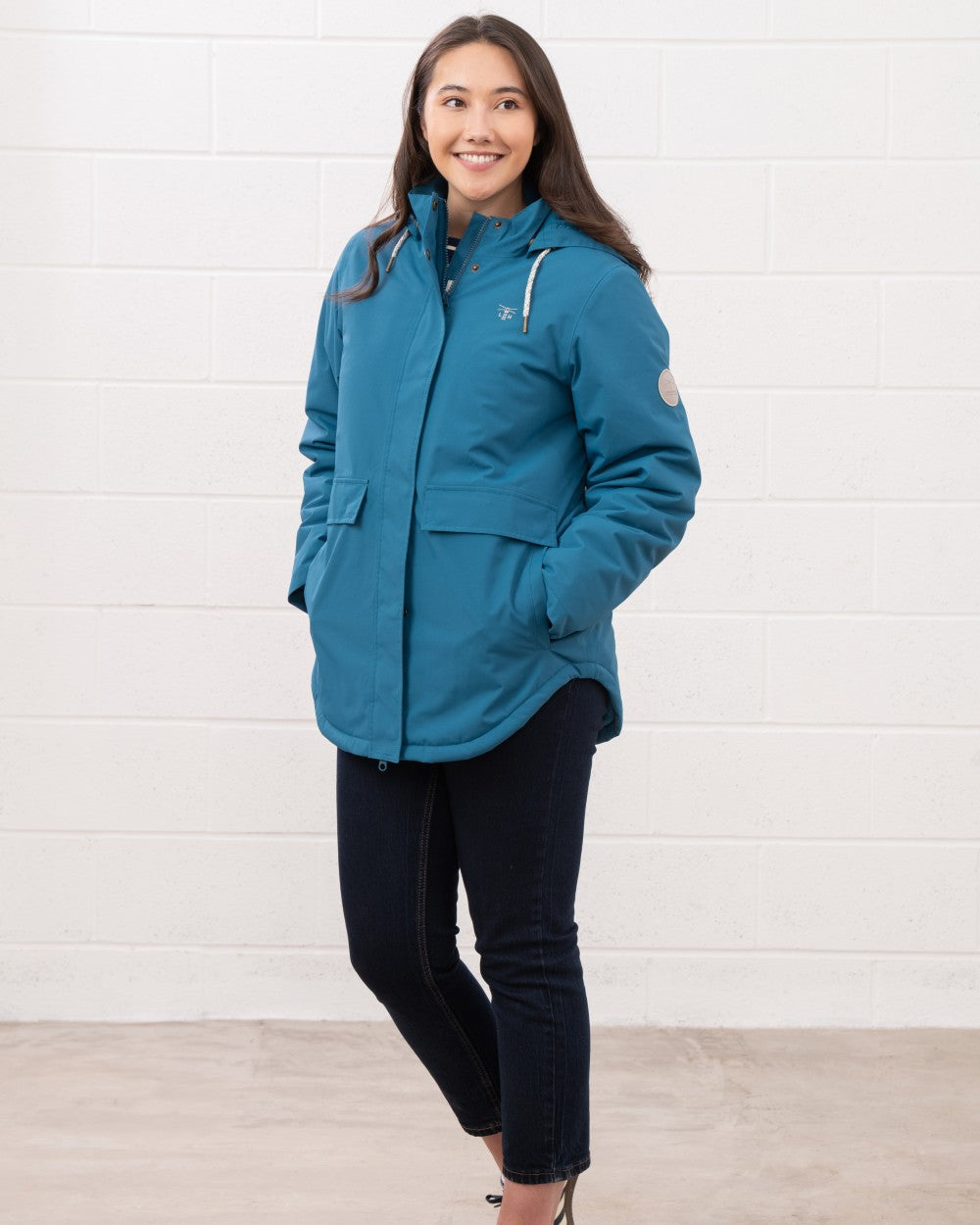 Teal coloured Lighthouse Ladies Tess Coat on wall background 