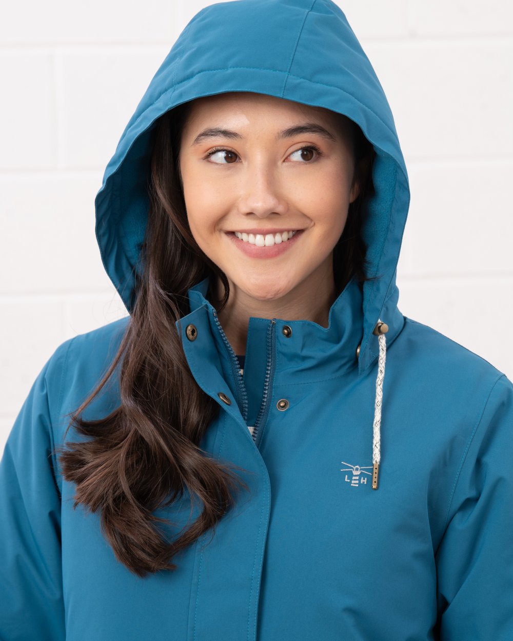 Teal coloured Lighthouse Ladies Tess Coat on wall background 
