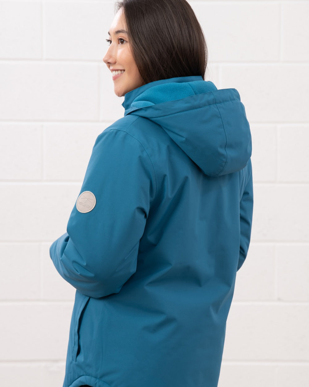 Teal coloured Lighthouse Ladies Tess Coat on wall background 