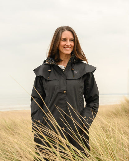 Black coloured Lighthouse Outback Full Length Ladies Waterproof Raincoat on beach background 