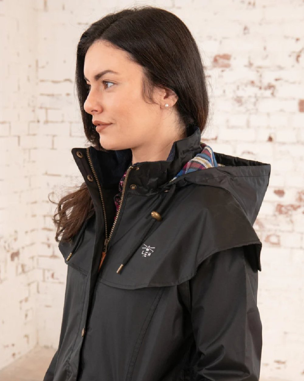 Black coloured Lighthouse Outback Full Length Ladies Waterproof Raincoat on wall background 
