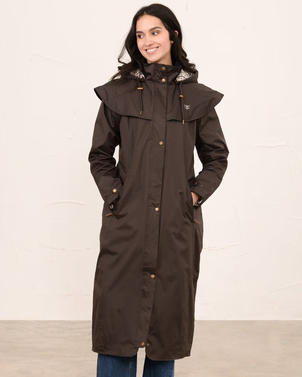 Chocolate coloured Lighthouse Outback Full Length Ladies Waterproof Raincoat on wall background 