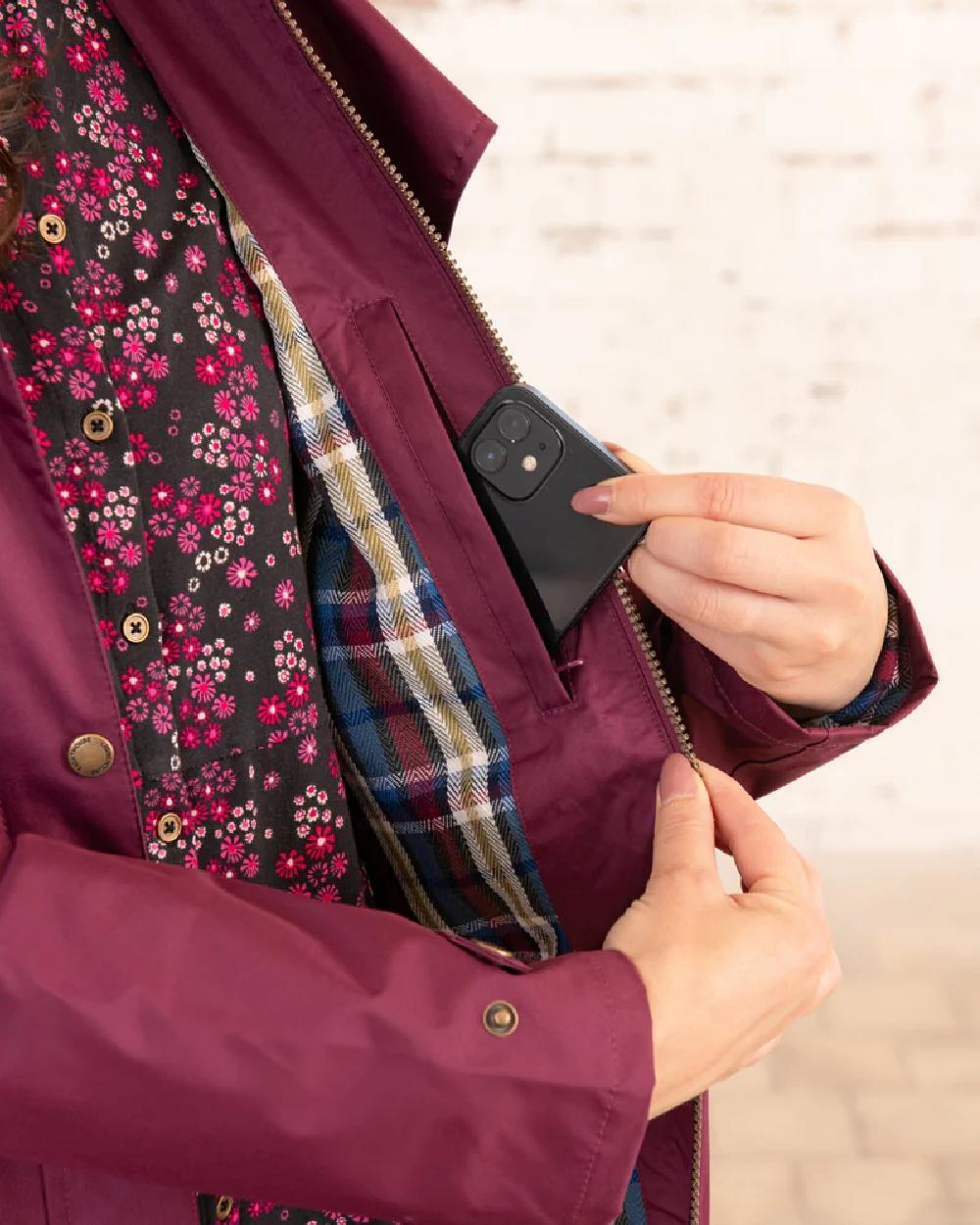 Plum coloured Lighthouse Outback Full Length Ladies Waterproof Raincoat on wall background 