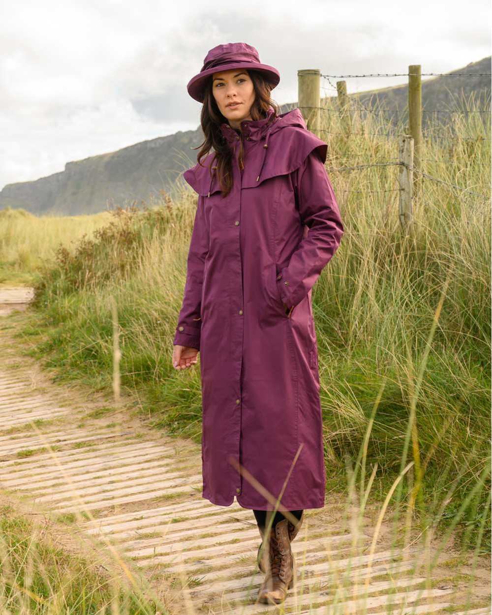 Plum coloured Lighthouse Outback Full Length Ladies Waterproof Raincoat on wood walk background 