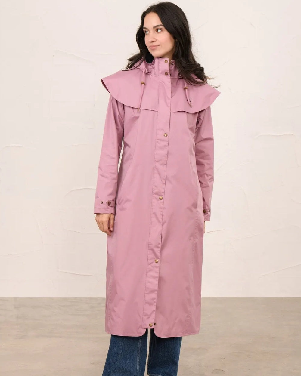 Wild Rose coloured Lighthouse Outback Full Length Ladies Waterproof Raincoat on wall background 