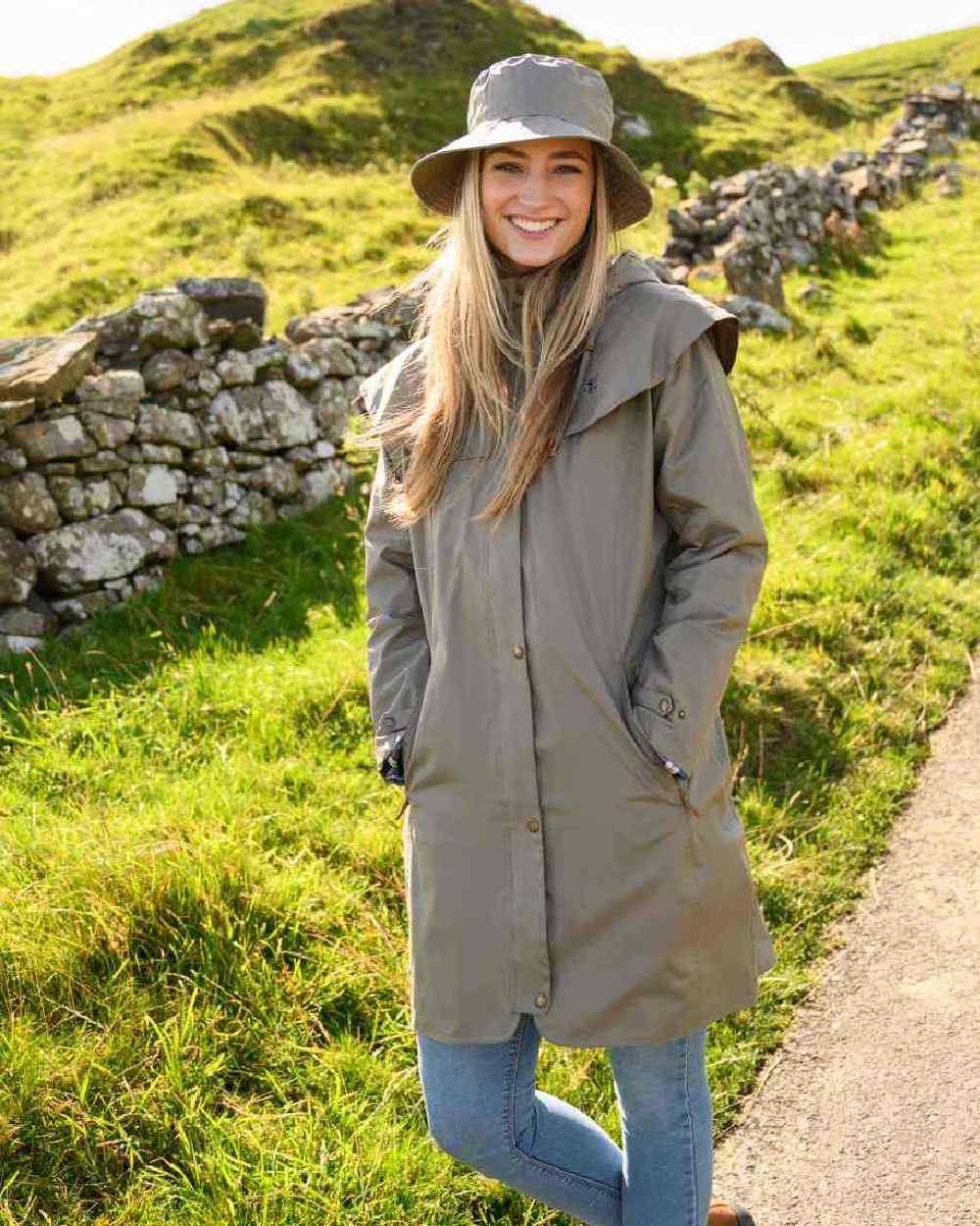 Fawn coloured Lighthouse Outrider 3/4 Length Ladies Waterproof Raincoat on grassy background 