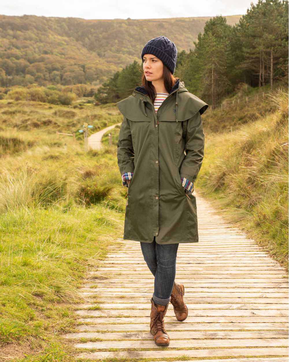 Fern coloured Lighthouse Outrider 3/4 Length Ladies Waterproof Raincoat on board walk background 