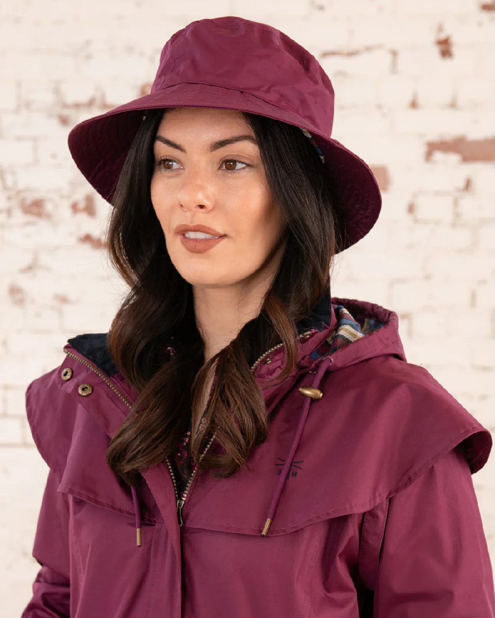 Plum coloured Lighthouse Storm Waterproof Hat on wall background 