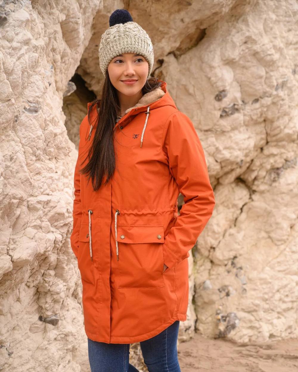 Burnt Orange coloured Lighthouse Isobel Ladies Coat on rock background 