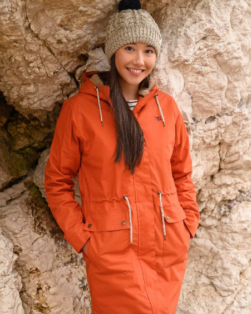 Burnt Orange coloured Lighthouse Isobel Ladies Coat on rock background 