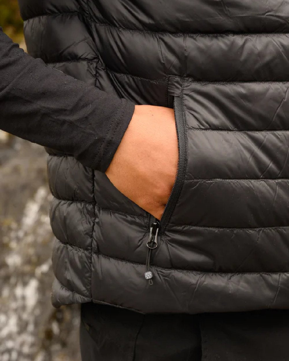 Jet Black coloured Mac In A Sac Mens Alpine Down Gilet on blurry mountain background 
