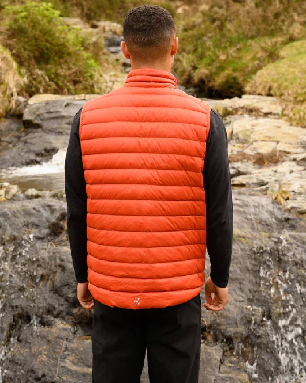 Burnt Orange coloured Mac In A Sac Mens Alpine Down Gilet on blurry mountain background 
