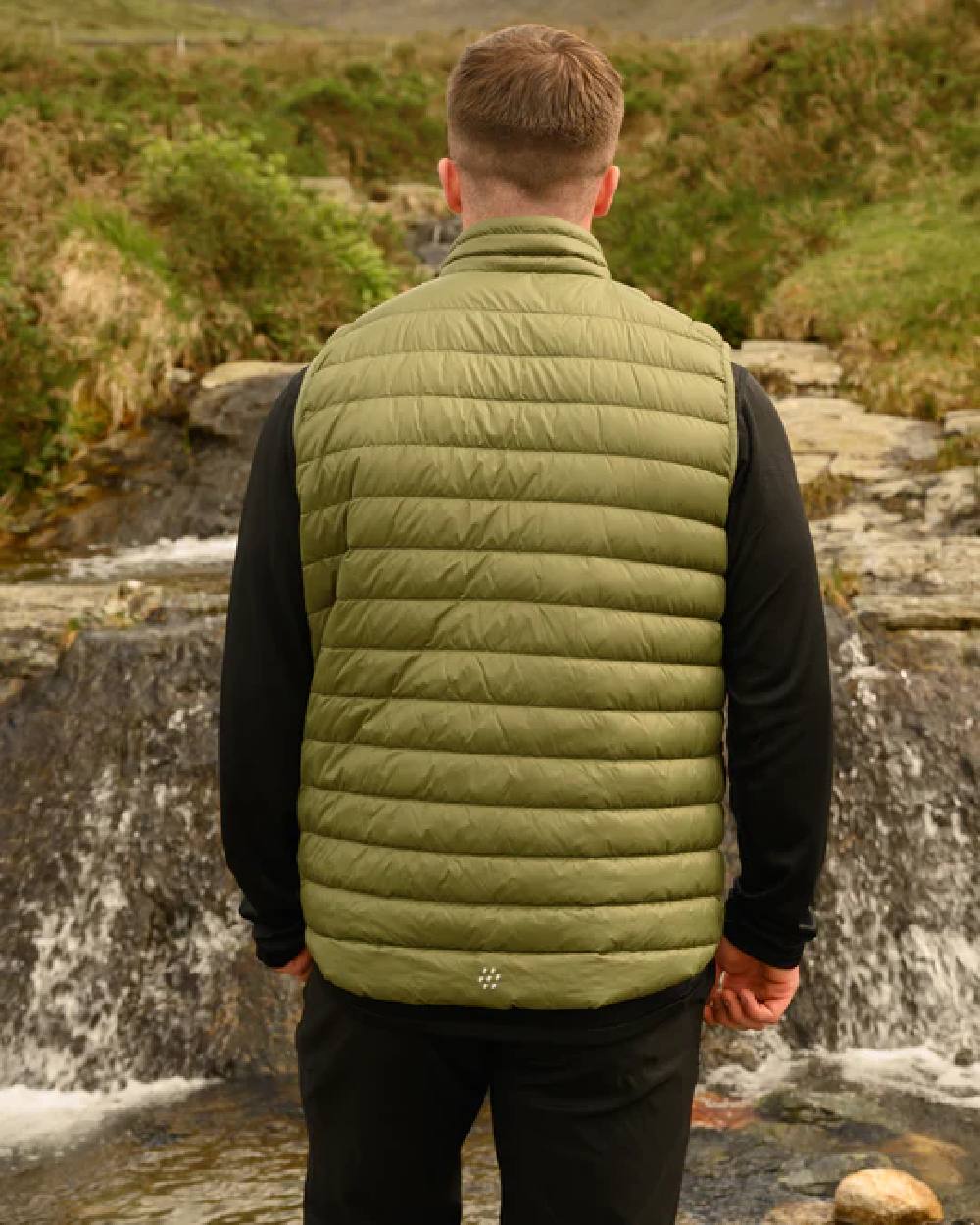 Khaki coloured Mac In A Sac Mens Alpine Down Gilet on blurry mountain background 