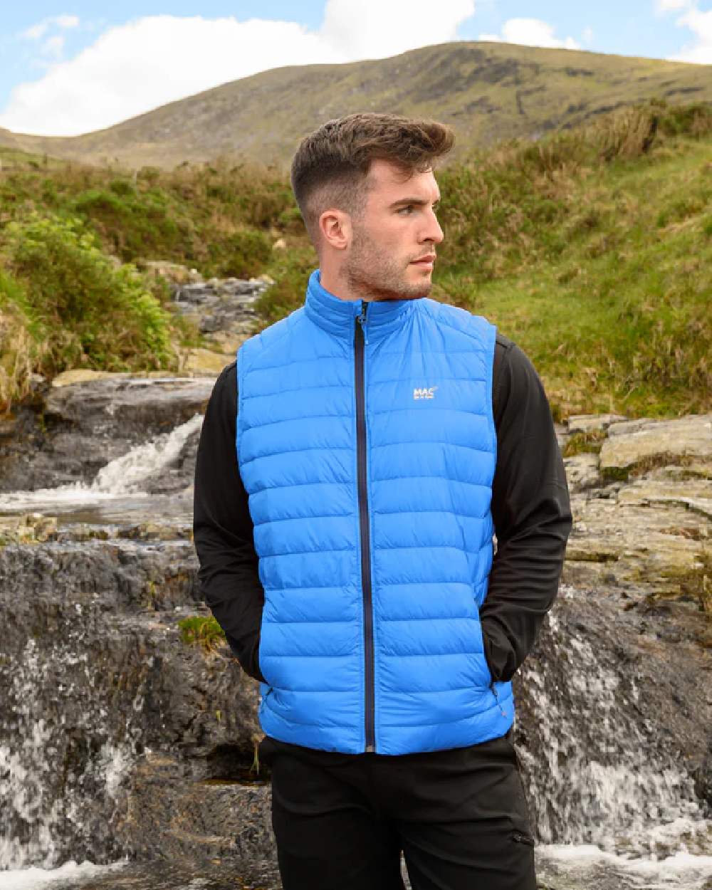 Royal coloured Mac In A Sac Mens Alpine Down Gilet on blurry green background 