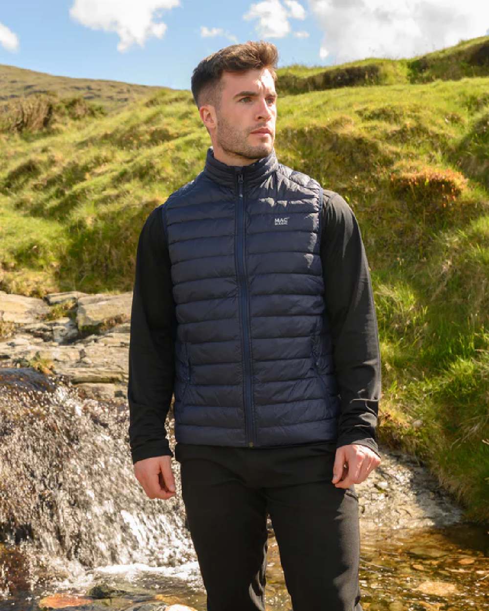 Navy coloured Mac In A Sac Mens Alpine Down Gilet on blurry mountain background 