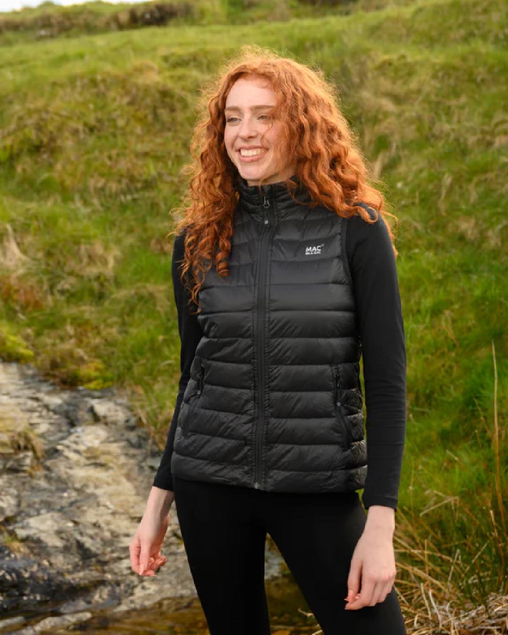 Black coloured Mac In A Sac Alpine Womens Down Gilet on green background 