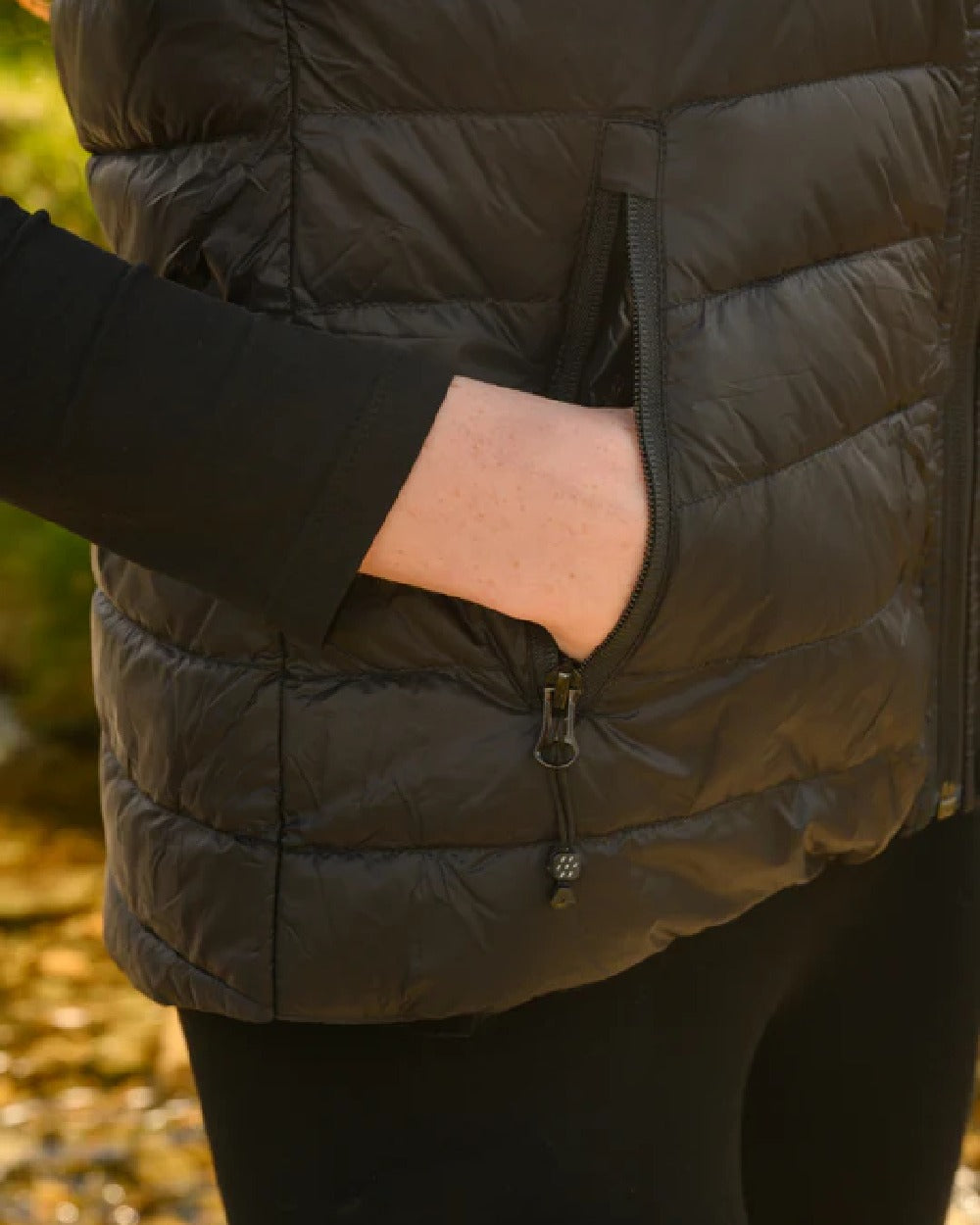 Black coloured Mac In A Sac Alpine Womens Down Gilet on green background 