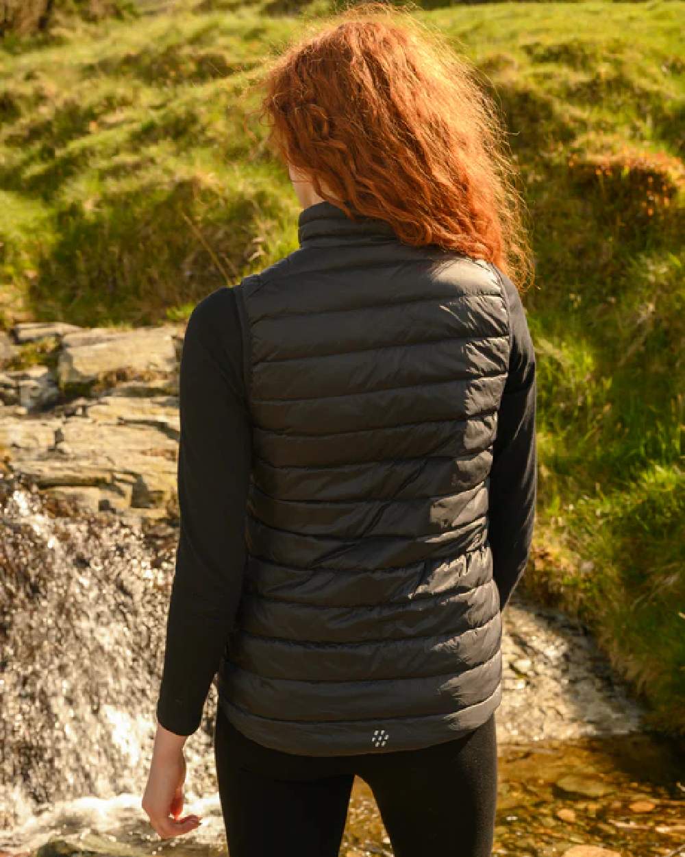 Black coloured Mac In A Sac Alpine Womens Down Gilet on green background 