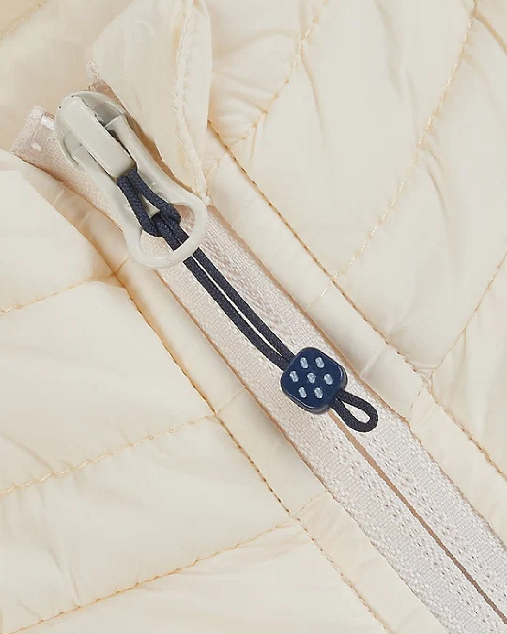Ivory coloured Mac In A Sac Alpine Womens Down Gilet on blurry background 