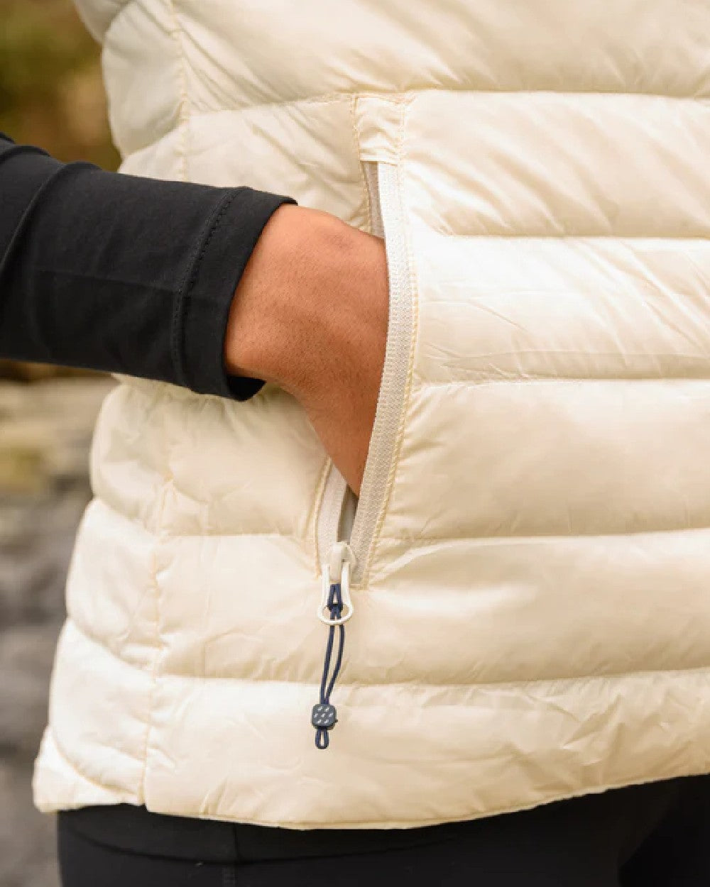 Ivory coloured Mac In A Sac Alpine Womens Down Gilet on blurry background 