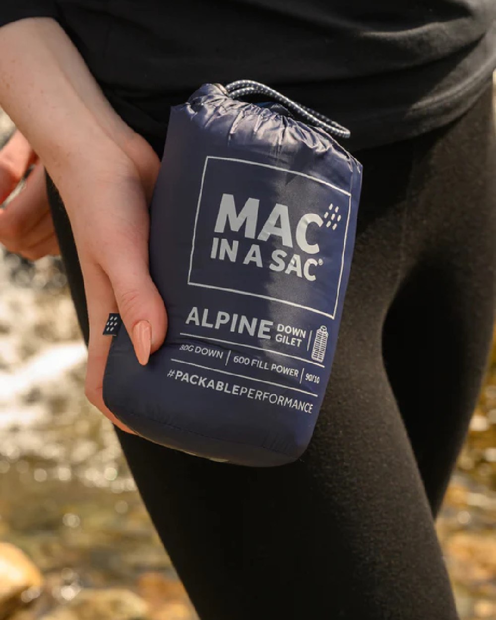 Navy coloured Mac In A Sac Alpine Womens Down Gilet on blurry background 