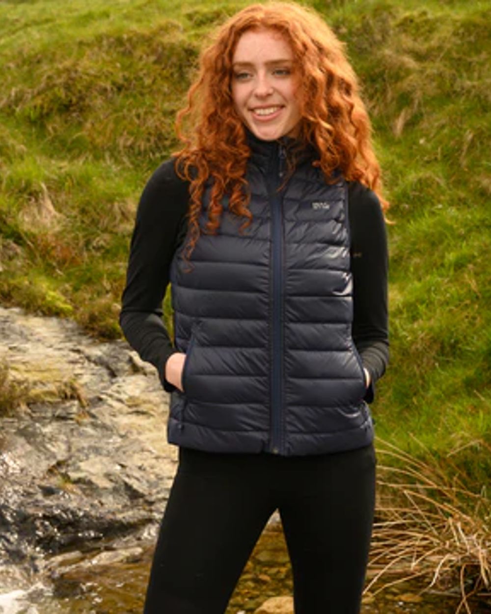 Navy coloured Mac In A Sac Alpine Womens Down Gilet on blurry background 