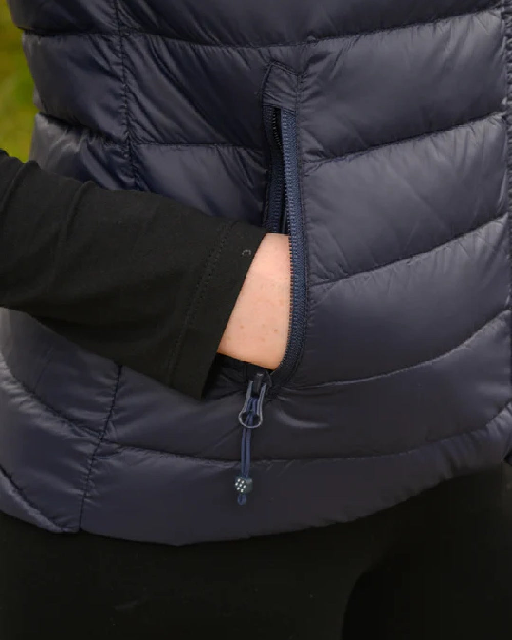 Navy coloured Mac In A Sac Alpine Womens Down Gilet on blurry background 