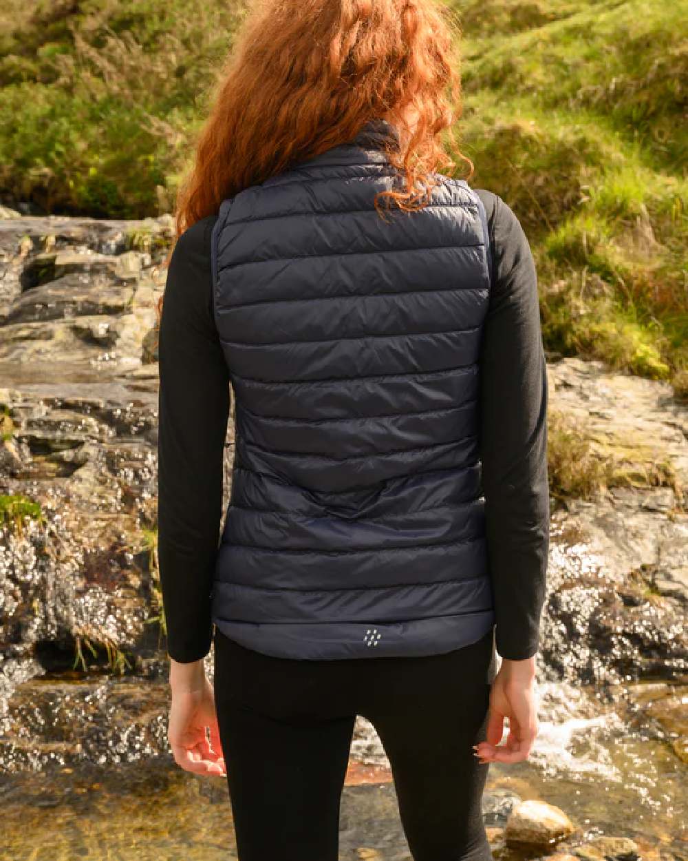 Navy coloured Mac In A Sac Alpine Womens Down Gilet on blurry background 