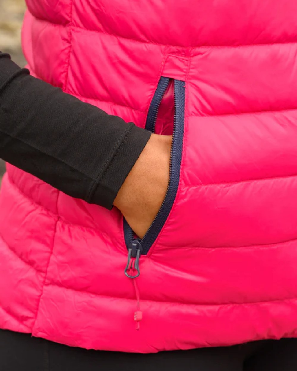 Pink coloured Mac In A Sac Alpine Womens Down Gilet on blurry background 