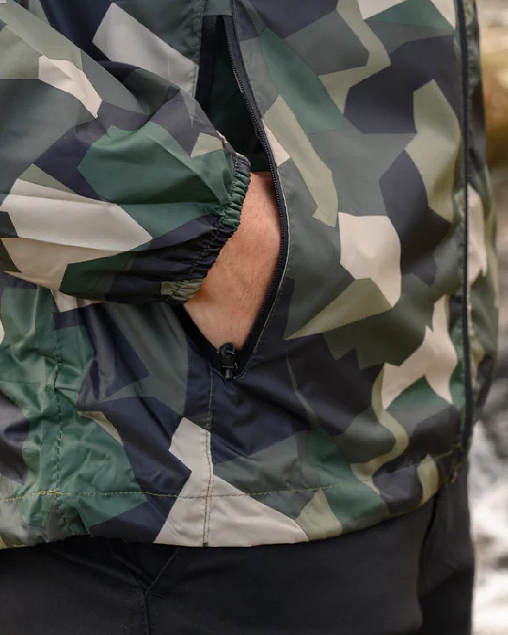 Green Camo Coloured Mac In A Sac Origin Camo Packable Waterproof Jacket on blurry background 