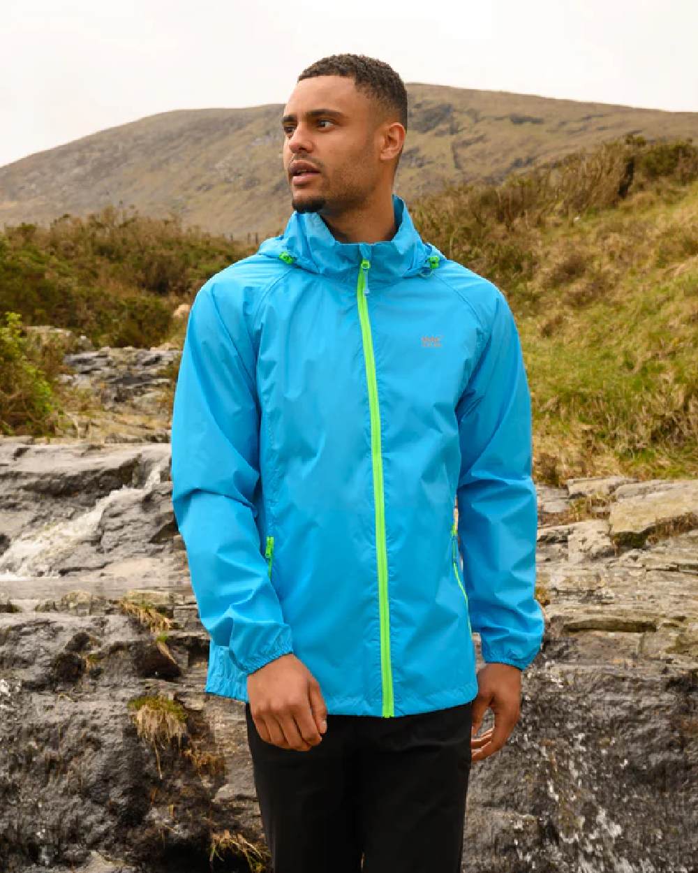 Neon Blue coloured Mac In A Sac Packable Origin Neon Waterproof Jacket on mountain background 