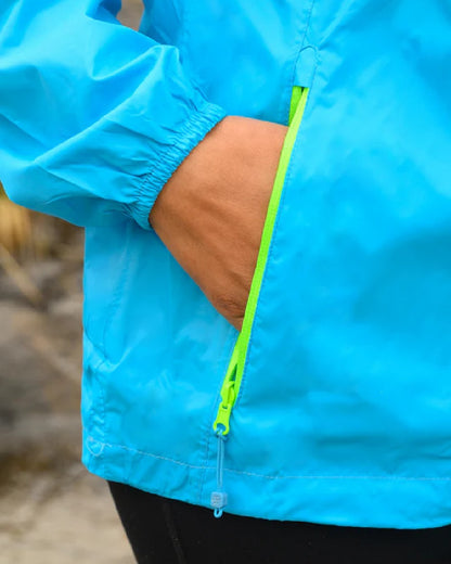 Neon Blue coloured Mac In A Sac Packable Origin Neon Waterproof Jacket on blurry mountain background 