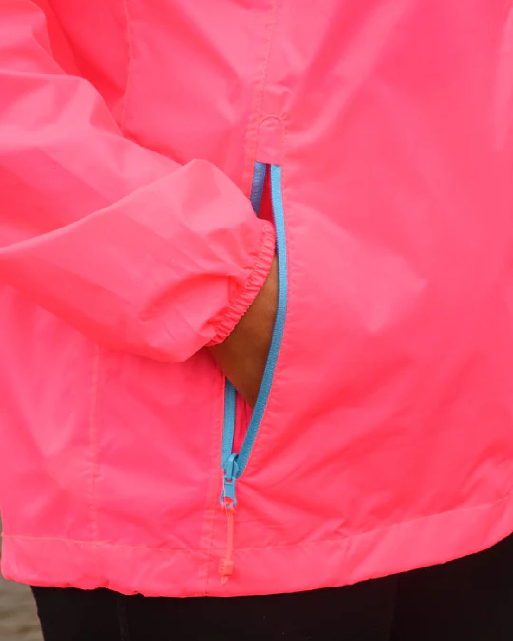 Neon Pink coloured Mac In A Sac Packable Origin Neon Waterproof Jacket on blurry background 