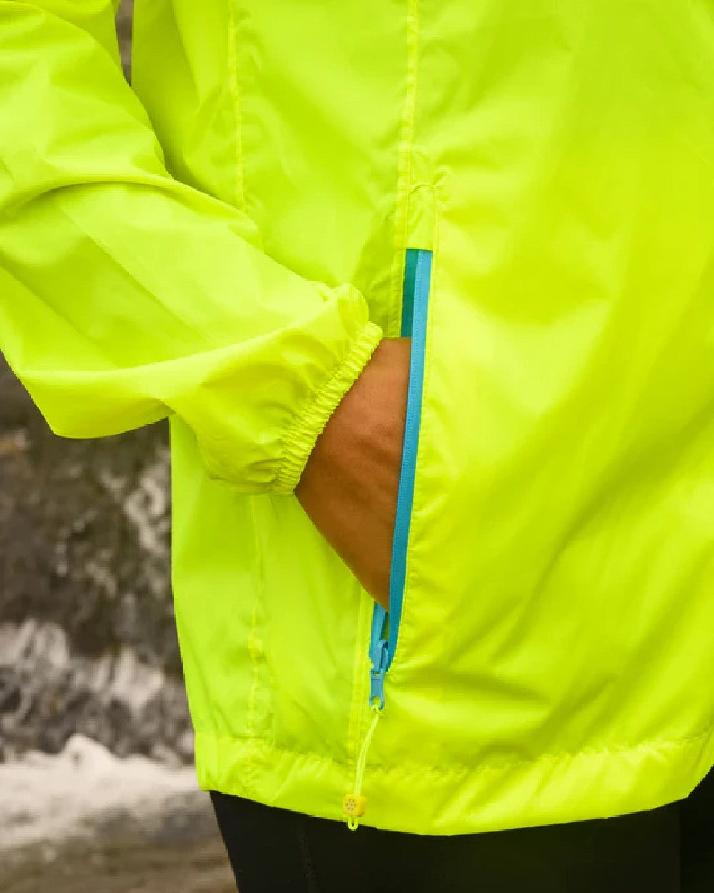 Neon Yellow coloured Mac In A Sac Packable Origin Neon Waterproof Jacket on blurry background 