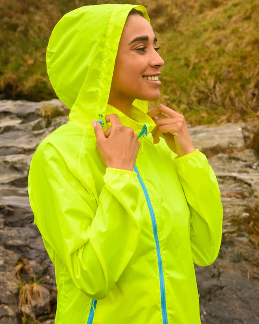 Neon Yellow coloured Mac In A Sac Packable Origin Neon Waterproof Jacket on blurry mountain background 