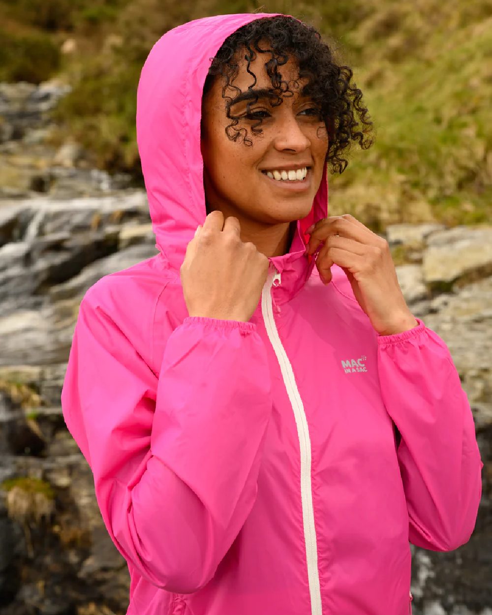 Pink Coloured Mac In A Sac Origin Packable Waterproof Jacket on blurry background 