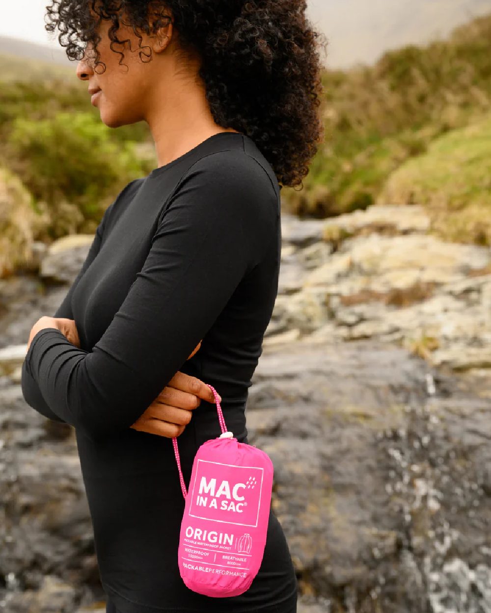 Pink Coloured Mac In A Sac Origin Packable Waterproof Jacket on blurry background 