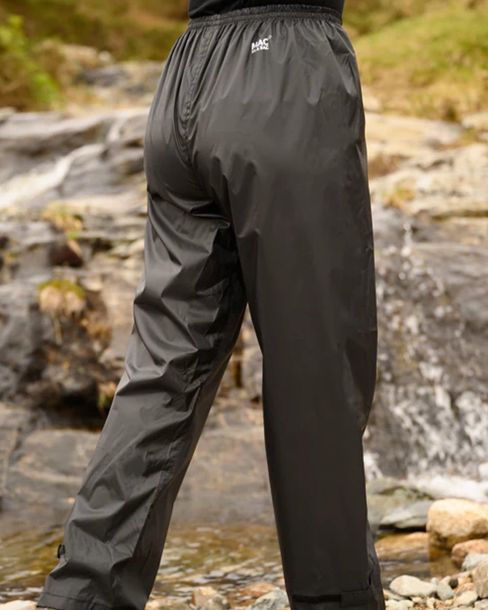 Black coloured Mac In A Sac Origin Packable Waterproof Overtrousers on blurry background 